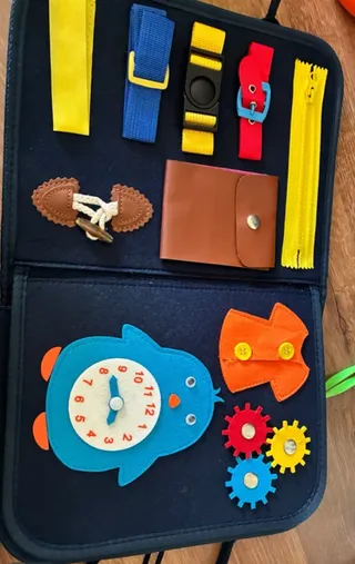 El tablero de actividades abierto, con cremallera, hebillas, cordones, un reloj de fieltro y engranajes