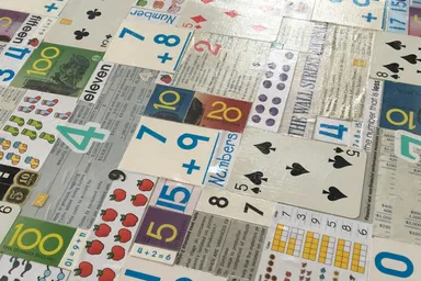 Cartas de baraja y tarjetas educativas con números y sumas extendidas sobre una mesa
