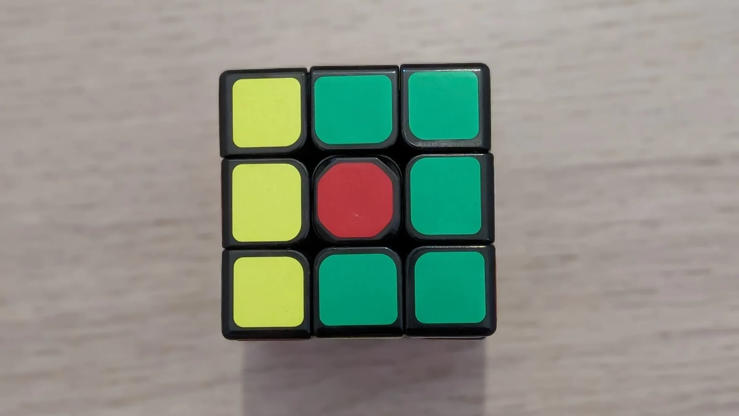 La cara de un cubo de Rubik de 3x3 a medio resolver, con una columna amarilla y el resto de cuadros verdes, vista desde arriba