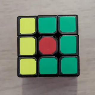 La cara de un cubo de Rubik de 3x3 a medio resolver, con una columna amarilla y el resto verde, vista desde arriba