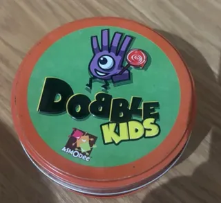 La lata verde y roja de Dobble Kids, de Asmodee, sobre una mesa de madera