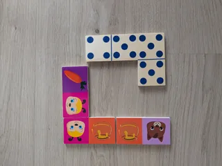 Fichas de dominó de madera colocadas sobre la mesa: unas con puntos azules y otras con dibujos de animales y comida