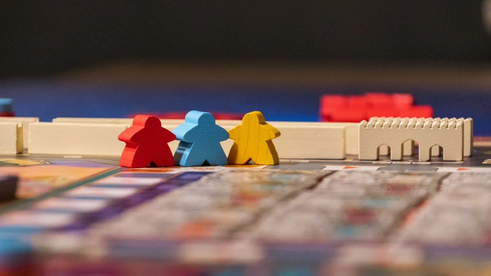 Tres fichas de madera roja, azul y amarilla sobre el tablero de un juego de mesa