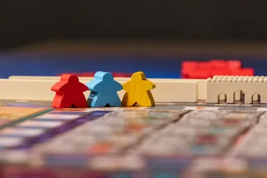 Tres fichas de madera roja, azul y amarilla sobre el tablero de un juego de mesa