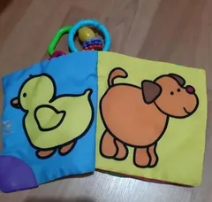 Un libro de tela abierto por las páginas del pato y el perro, con las anillas de colores arriba