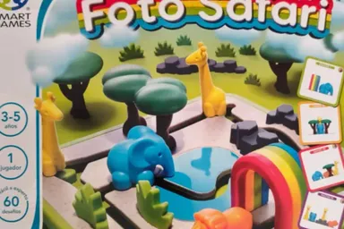 La caja de Foto Safari, con la jirafa, el elefante y el hipopótamo de plástico colocados entre árboles junto a un charco y un arcoíris