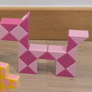 Una serpiente mágica rosa de piezas grandes, montada en forma de perro con cuatro patas, la cabeza levantada y la cola en alto